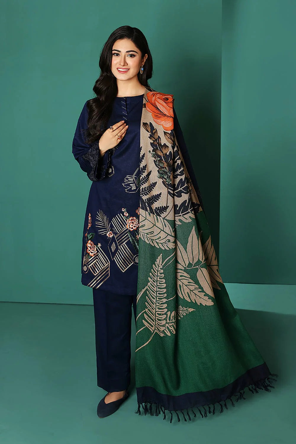 Woman wearing a navy blue outfit with a green and beige patterned scarf against a teal background