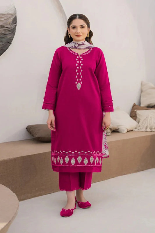 Woman wearing a pink traditional outfit with intricate designs in a minimalistic setting.