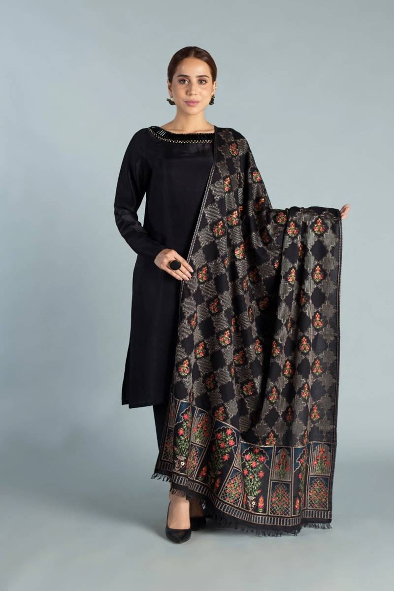 Woman holding a black patterned scarf against a gray background
