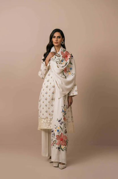 Woman wearing a white embroidered outfit against a beige background