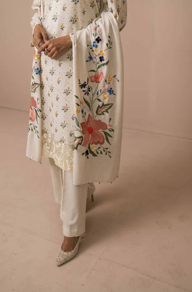 Person wearing a floral embroidered kurta with white pants on a beige background