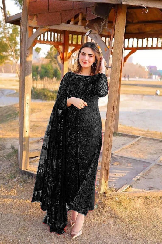 Woman in a black lace dress standing under a wooden gazebo.