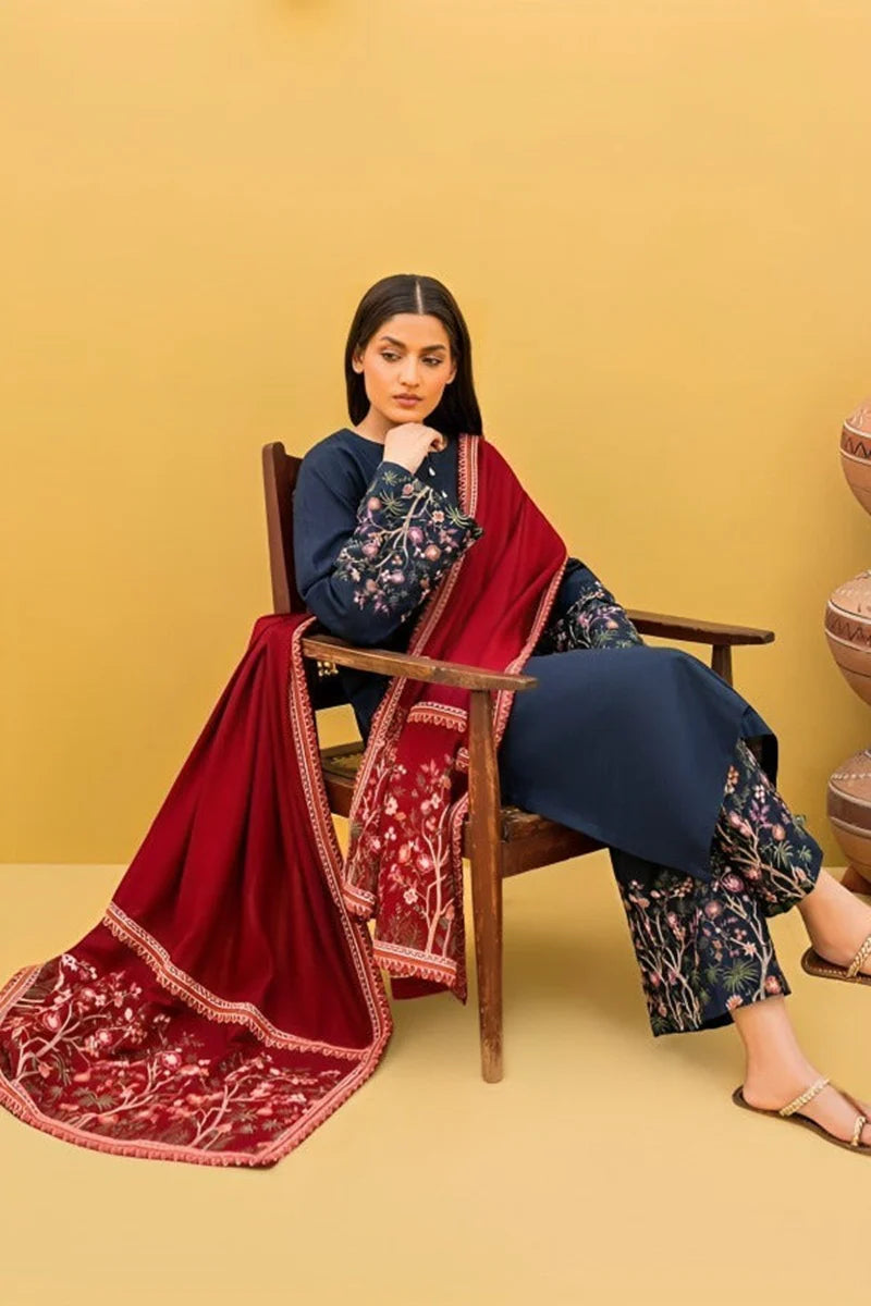 Woman sitting on a chair with a red and gold dupatta draped over her shoulders against a yellow background