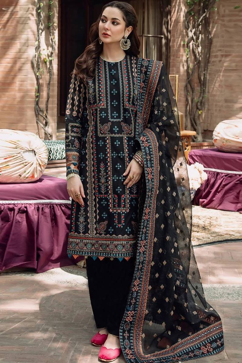 Woman in traditional embroidered outfit standing outdoors with decorative background